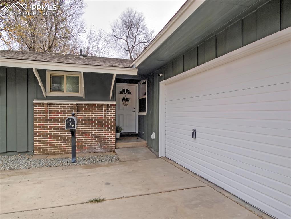Image 3 of 26: Doorway to property featuring board and batten siding and brick siding