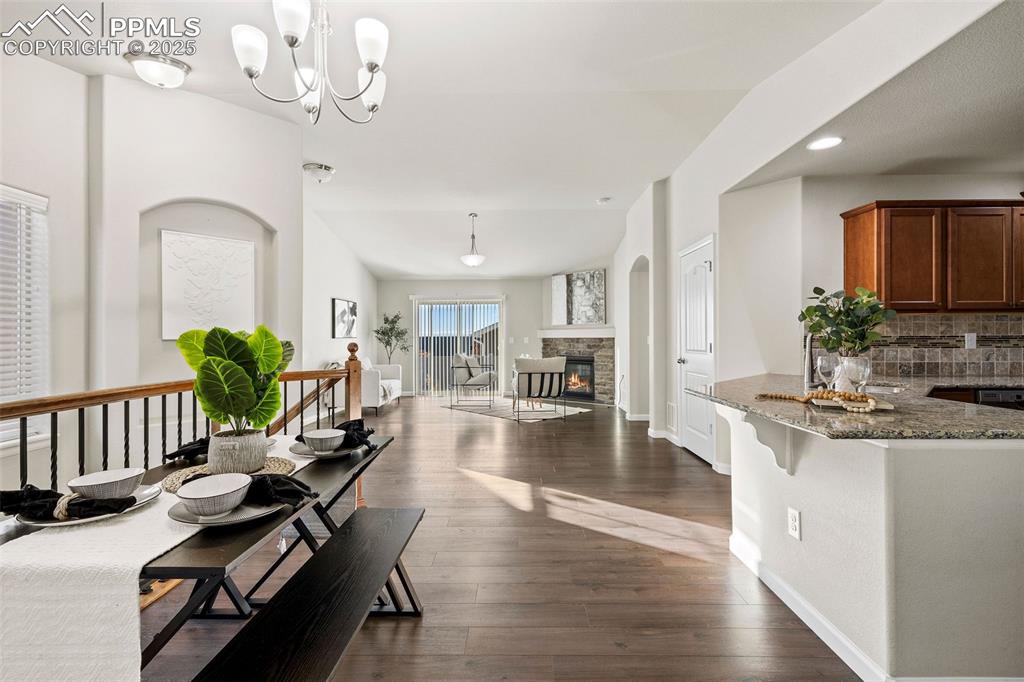 Image 13 of 42: Dining area with dark wood-style floors, a stone fireplace, and recessed li