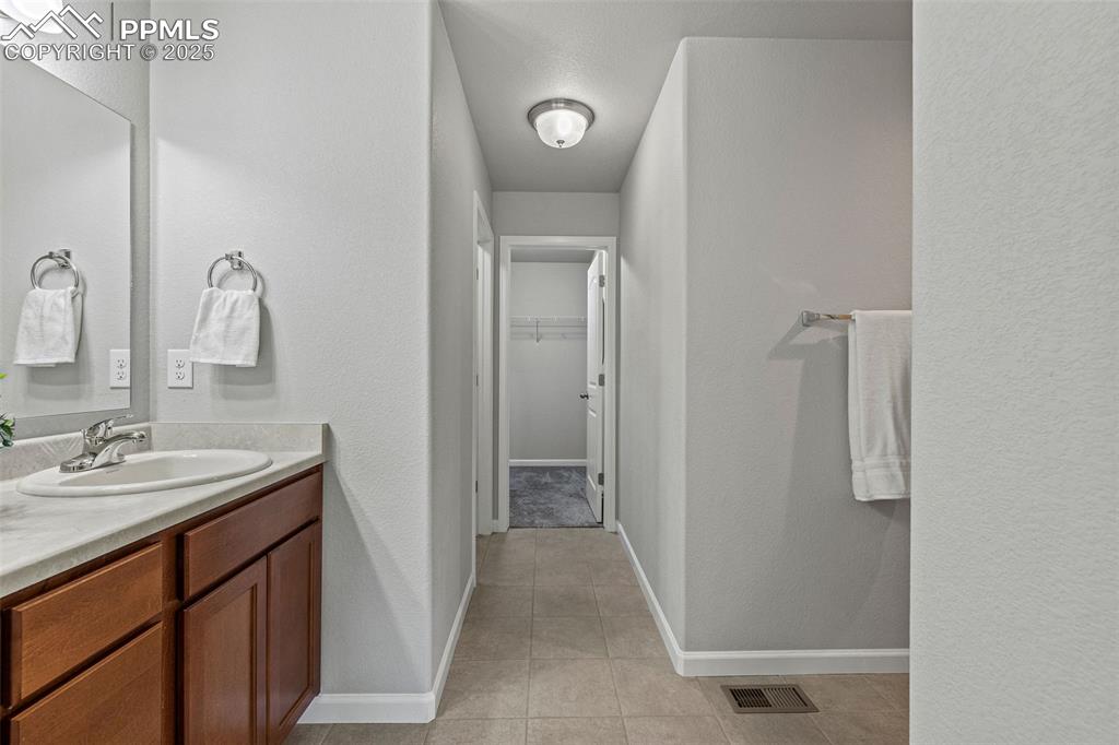 Image 16 of 42: Bathroom featuring a textured wall, vanity, light tile patterned flooring,
