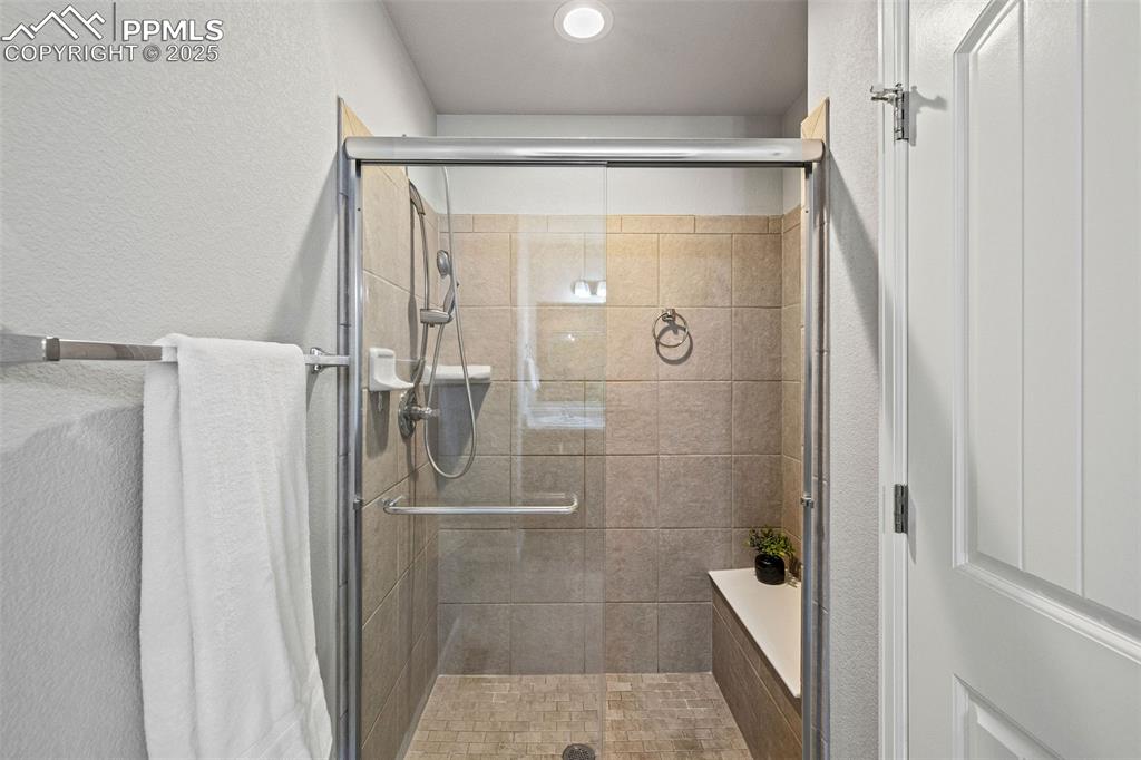 Image 17 of 42: Bathroom with a textured wall and a stall shower