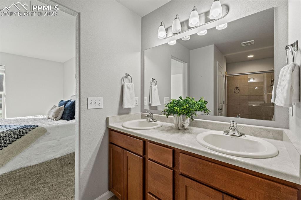 Image 18 of 42: Full bathroom featuring double vanity, a shower stall, ensuite bathroom, an