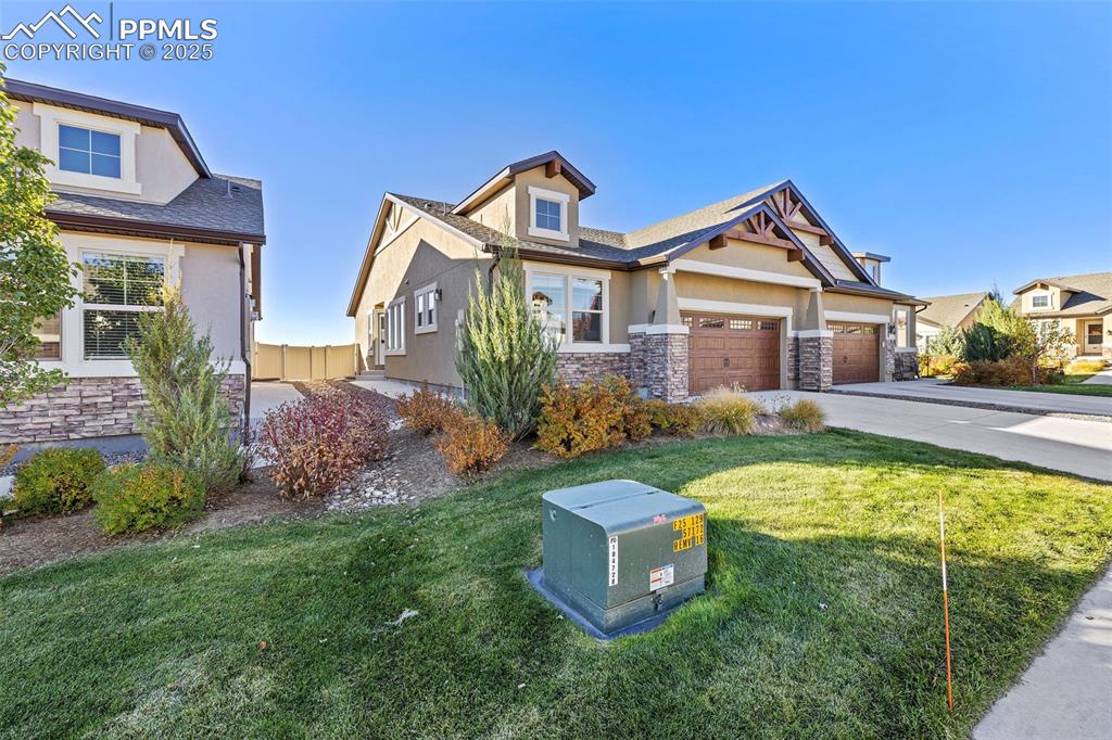 Image 32 of 42: Craftsman-style home featuring stucco siding, stone siding, a front yard, a
