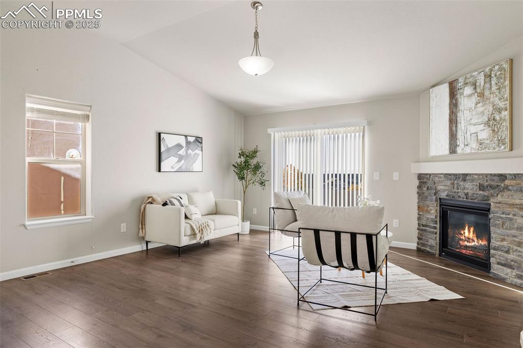 Image 6 of 42: Living room featuring vaulted ceiling, dark wood-type flooring, and a firep