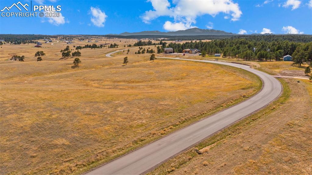 Image 4 of 17: Paved road extending through open, golden fields with scattered trees
