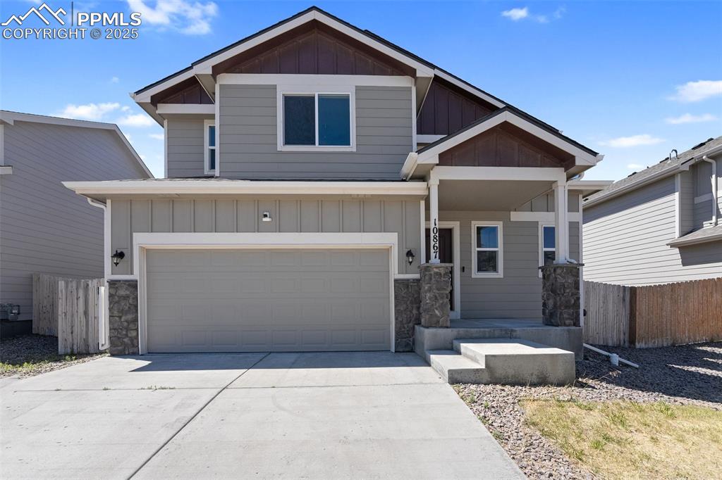 Caption: View of front of home with board and batten siding, stone siding, concrete driveway, and a garage