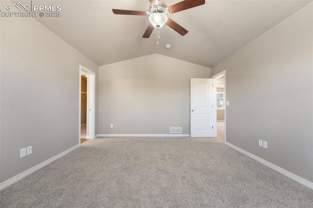 Image 18 of 25: Unfurnished room with vaulted ceiling, a ceiling fan, and carpet