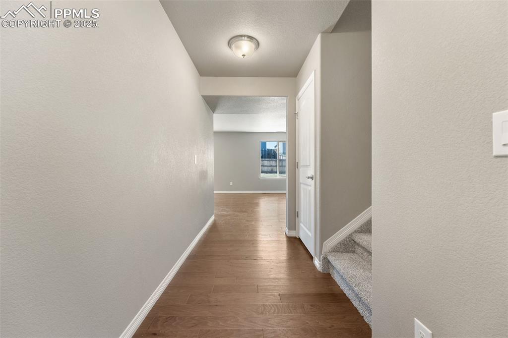 Image 21 of 25: Hallway featuring wood finished floors, a textured wall, and stairway