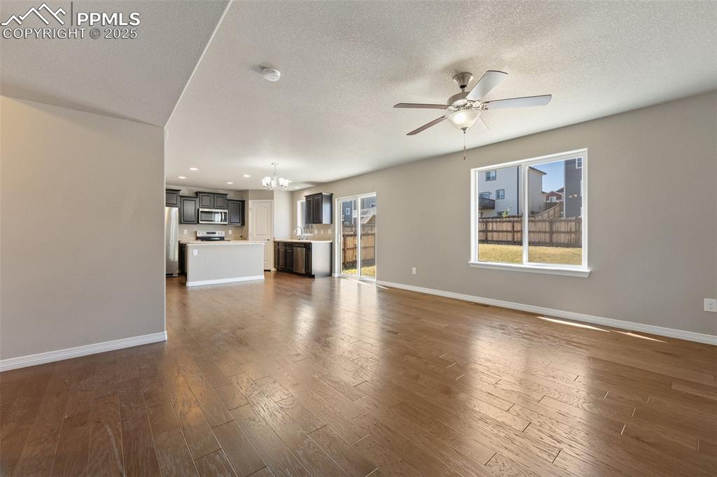 Image 25 of 25: Unfurnished living room with a chandelier, ceiling fan, a textured ceiling,