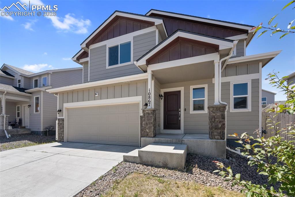 Image 3 of 25: View of front facade featuring board and batten siding, concrete driveway,