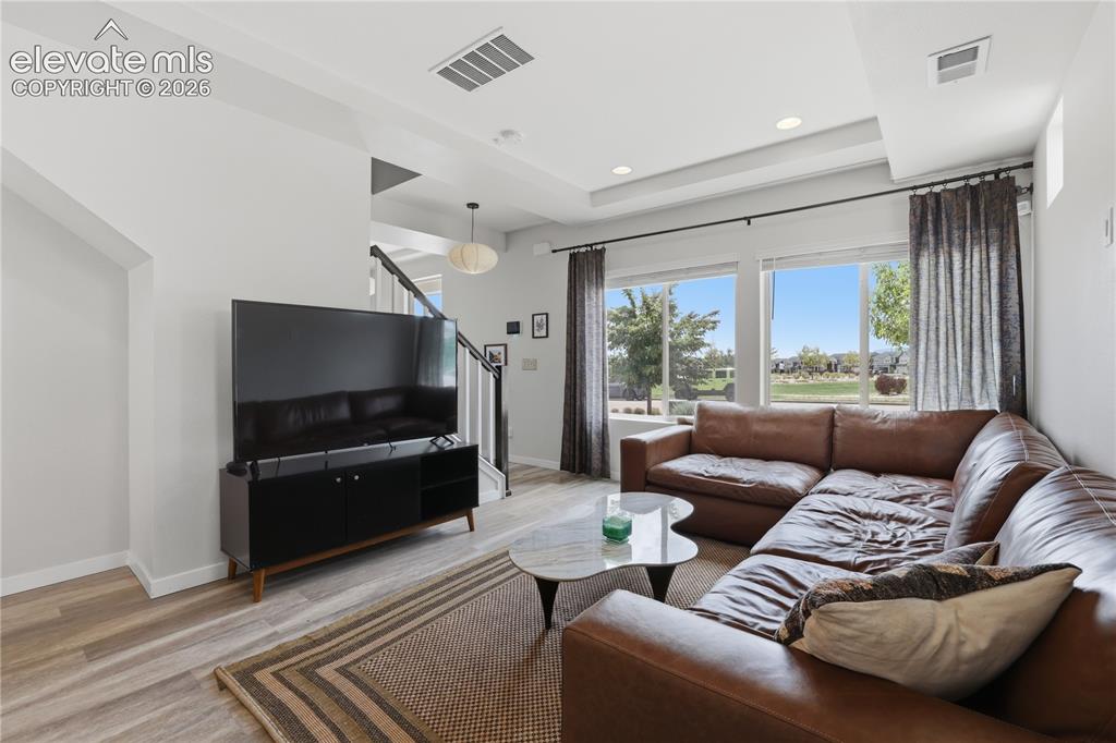 Image 10 of 48: Spacious living area featuring large windows, wood-finish flooring, recesse