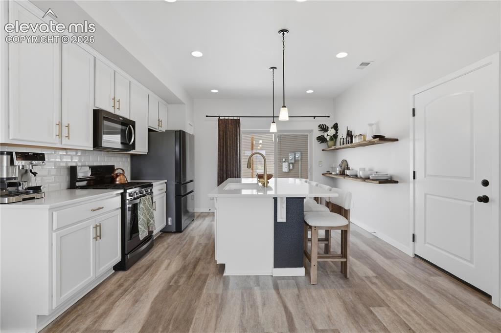 Image 11 of 48: Modern kitchen with white cabinetry and gold-tone hardware, featuring a whi