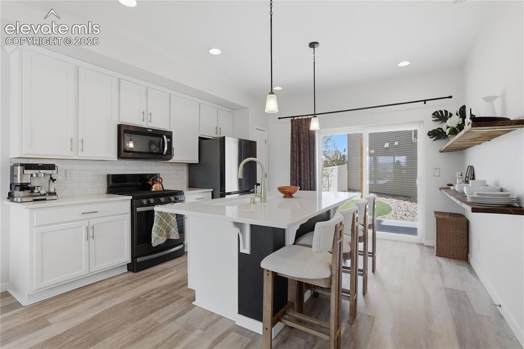 Image 12 of 48: Contemporary kitchen featuring white cabinetry, a central island with count