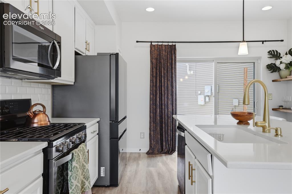 Image 13 of 48: Contemporary kitchen featuring white cabinetry, a white subway tile backspl