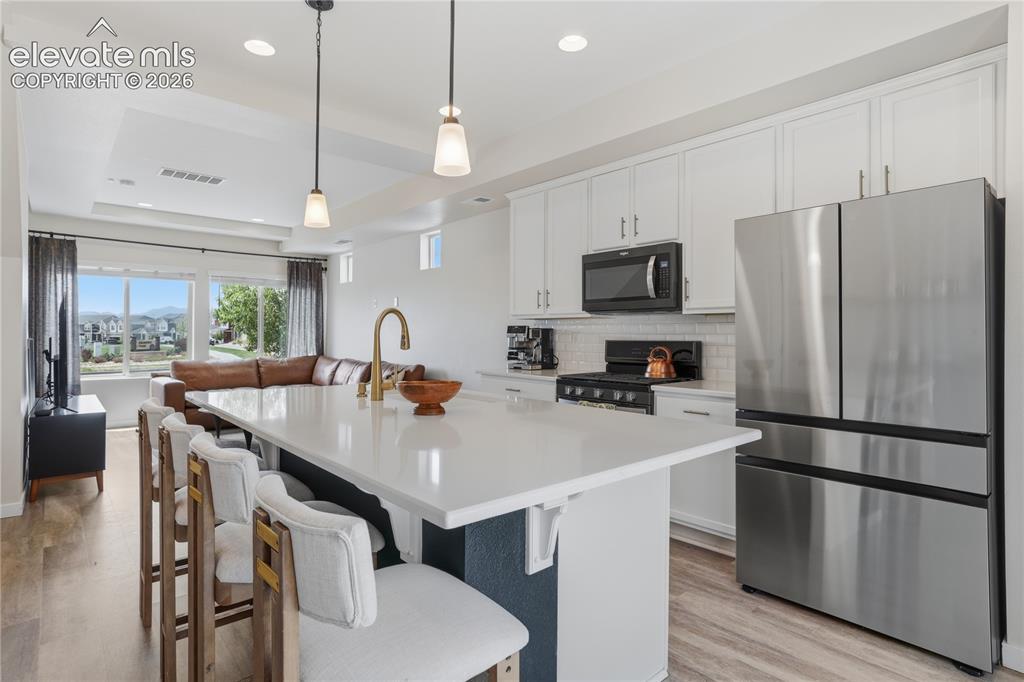 Image 15 of 48: Open-concept kitchen featuring a quartz island with seating, stainless stee