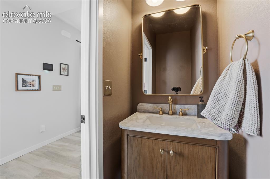 Image 17 of 48: Bathroom vanity featuring a light-toned countertop, brass-finish faucet, an