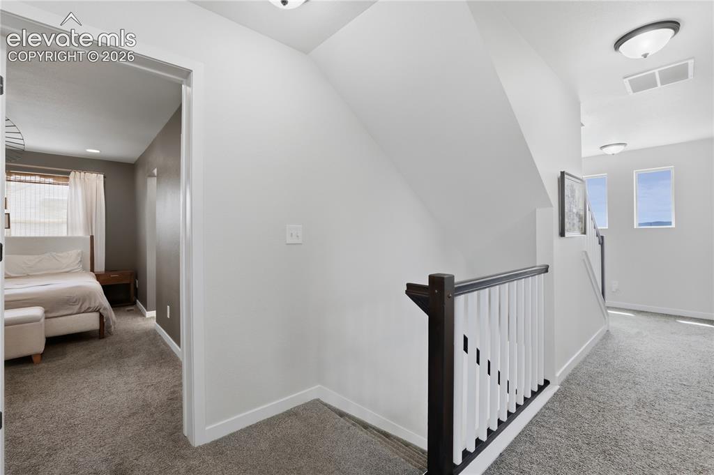 Image 18 of 48: Carpeted hallway featuring a staircase with contemporary dark wood and whit