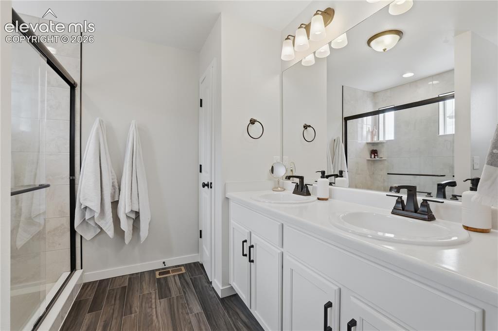Image 22 of 48: Dual vanity with white cabinetry and solid surface countertops