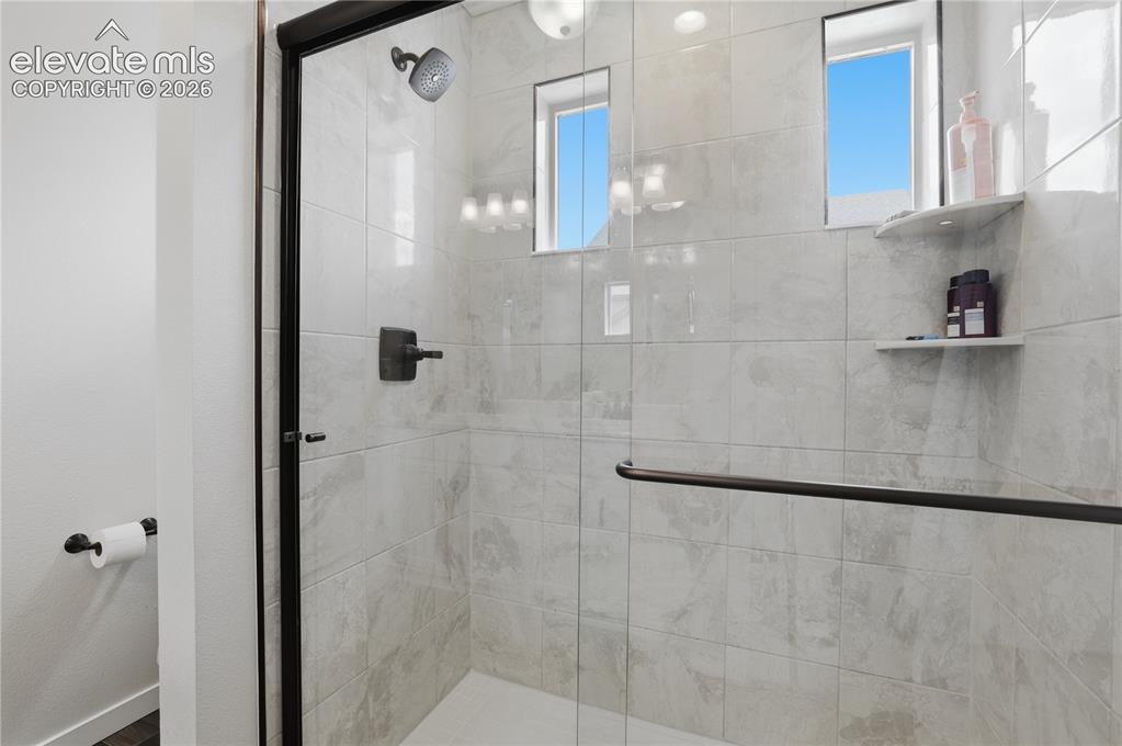 Image 23 of 48: Shower enclosure with a black-framed glass door, tiled walls, a dark bronze