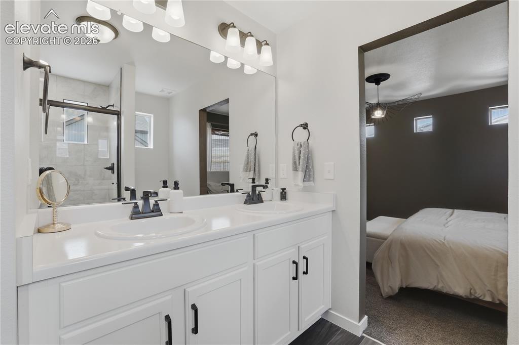 Image 24 of 48: Dual vanity with white cabinetry and dark hardware