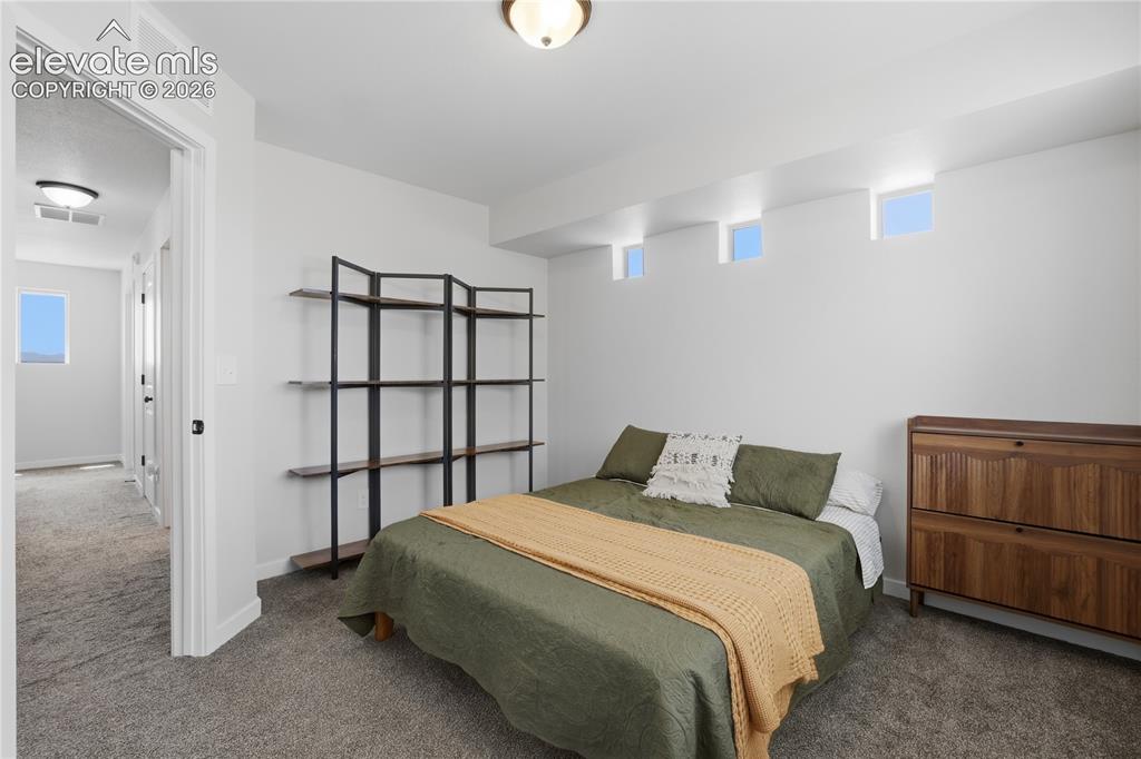 Image 26 of 48: Carpeted bedroom featuring white walls and multiple transom windows
