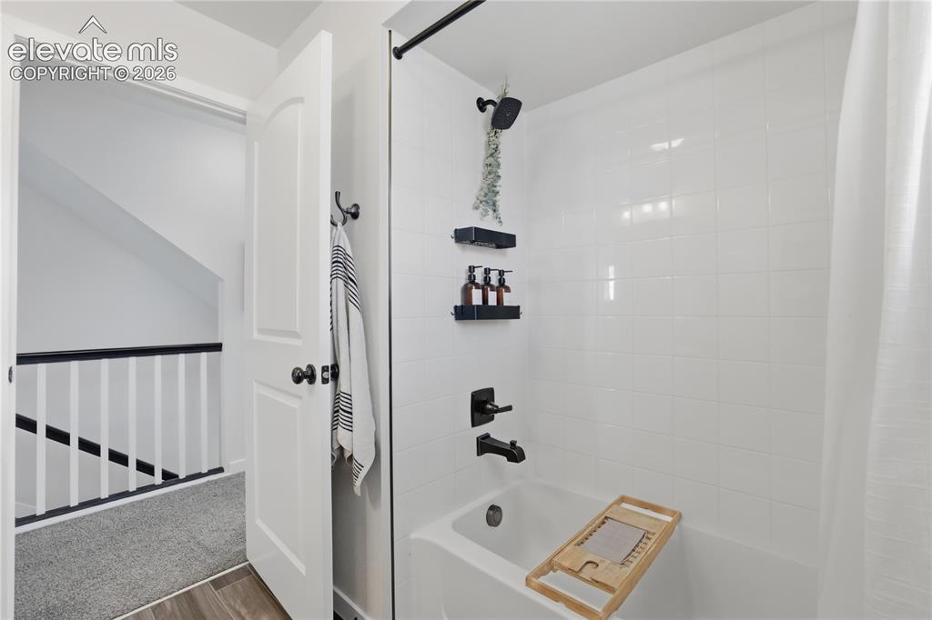 Image 29 of 48: Bathtub and shower combination featuring white subway tile surround, matte