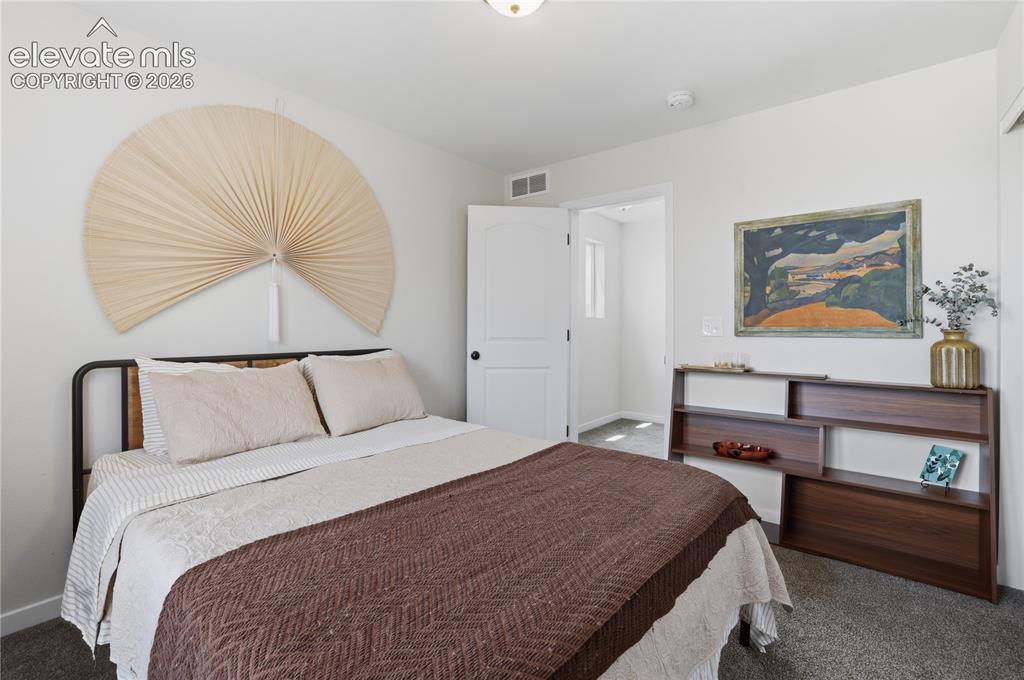Image 31 of 48: Bedroom featuring light gray walls, dark gray carpet, a white paneled door,