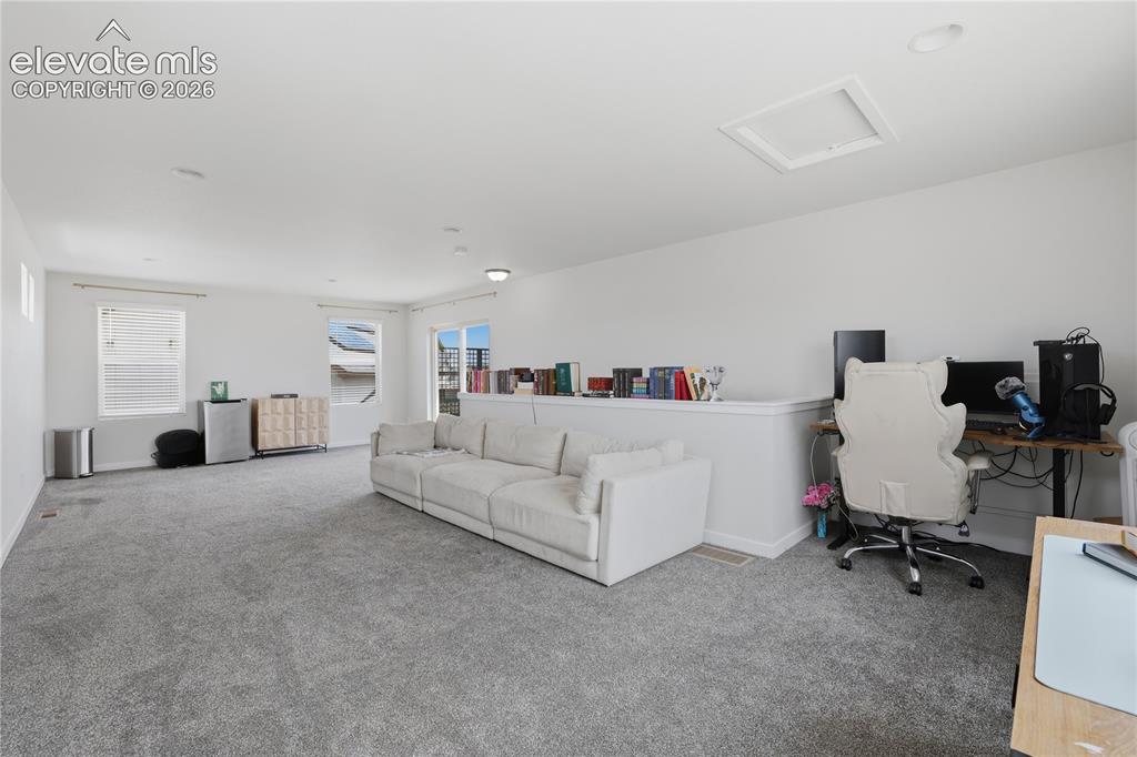 Image 35 of 48: Spacious carpeted room featuring multiple windows, a half-wall partition, a