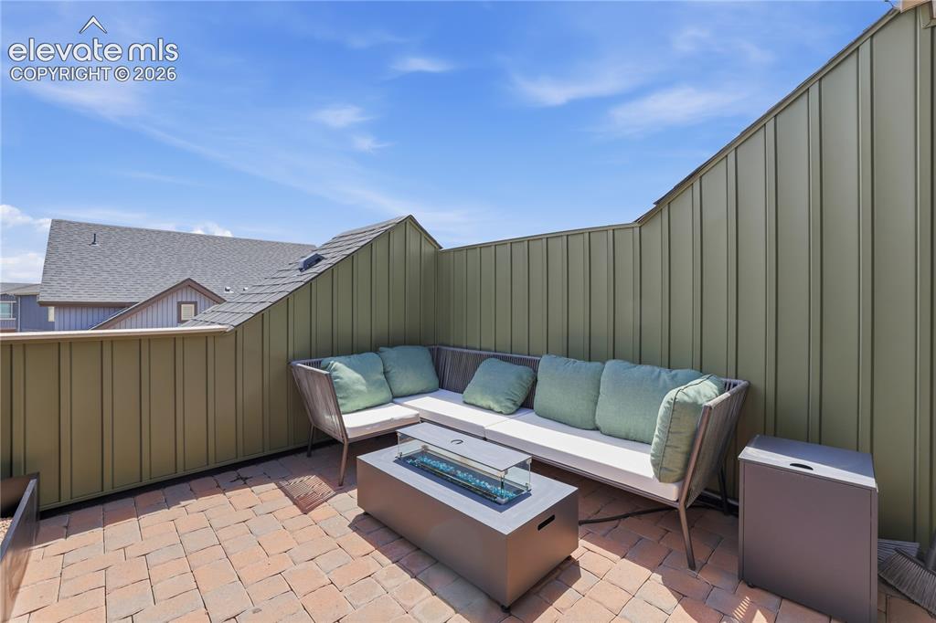 Image 41 of 48: Private rooftop patio featuring brick paver flooring, board-and-batten styl