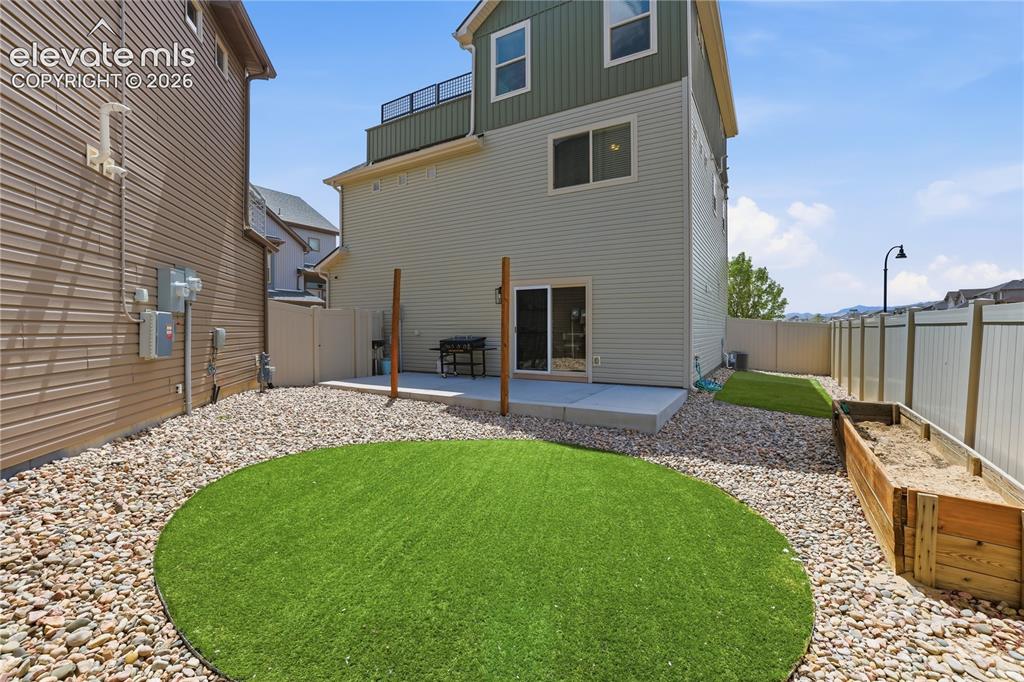 Image 43 of 48: Rear exterior with a concrete patio, sliding glass door, and a circular art