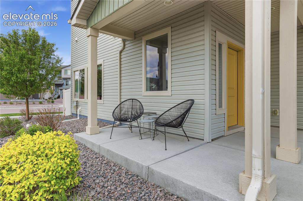 Image 5 of 48: Inviting covered front porch with concrete flooring and a vibrant yellow en