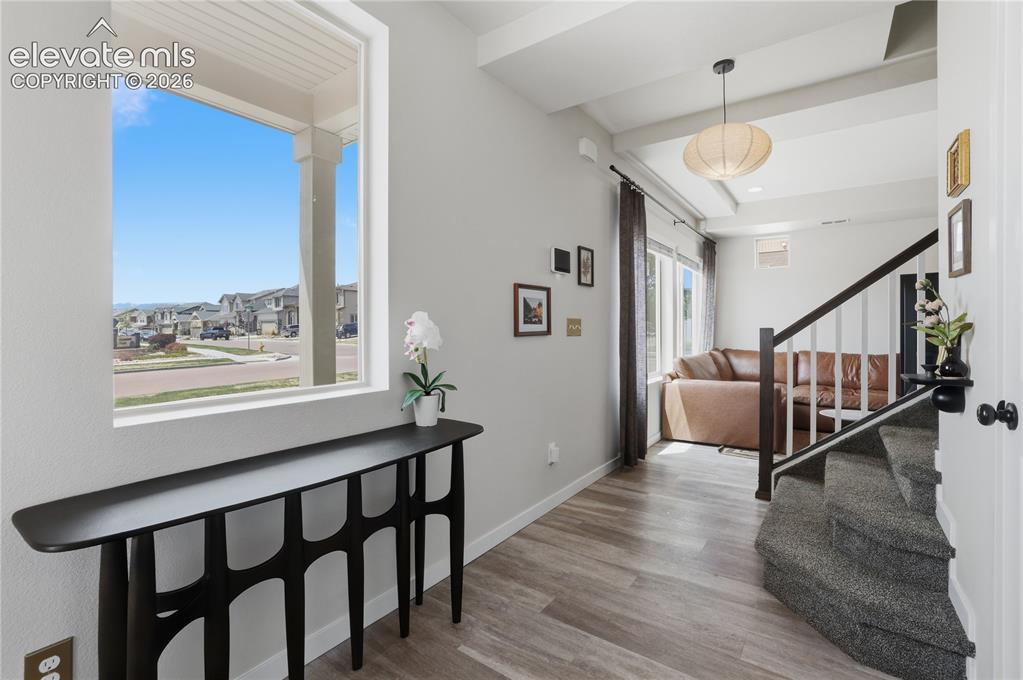 Image 7 of 48: Bright entryway featuring a large window, wood-finish flooring, and exposed