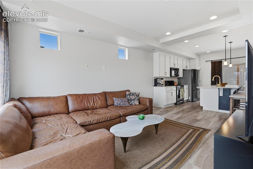Image 8 of 48: Open-concept living space featuring wood-finish flooring, recessed lighting