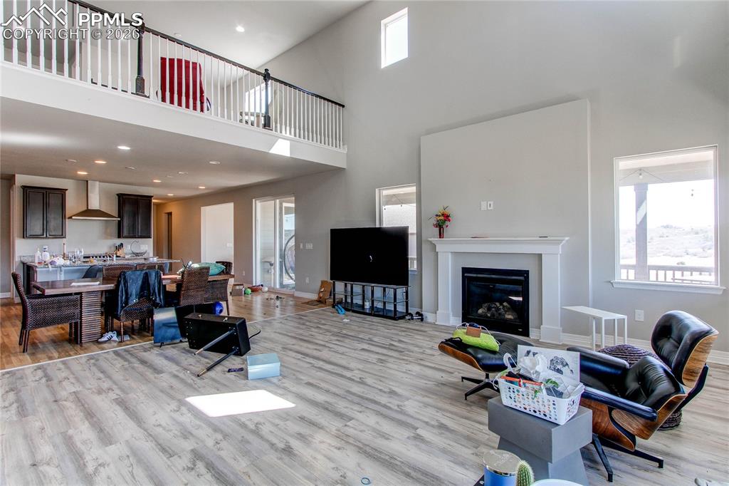 Image 27 of 49: Living room featuring light wood-style floors, a high ceiling, a glass cove
