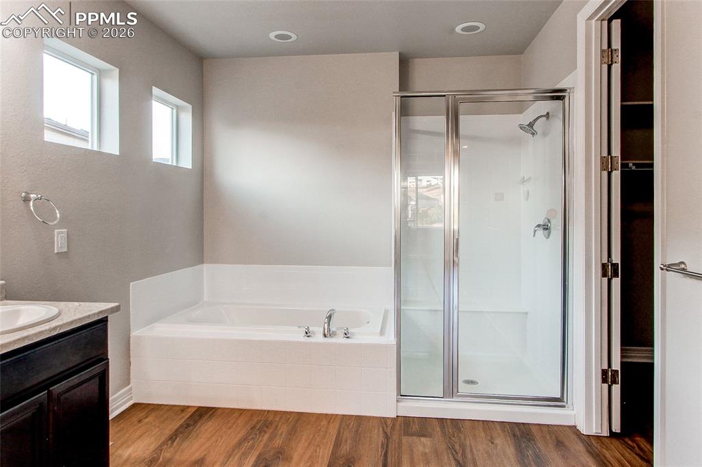 Image 30 of 49: Bathroom featuring vanity, wood finished floors, a stall shower, and a gard