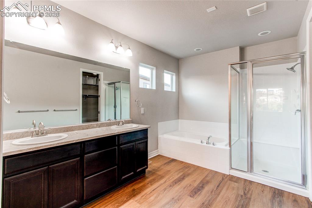 Image 31 of 49: Bathroom featuring double vanity, light wood-style floors, a shower stall, 
