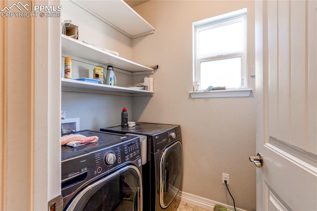 Image 44 of 49: Laundry room with washer and clothes dryer and baseboards