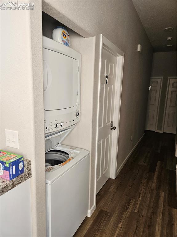 Image 7 of 12: Laundry room featuring dark wood finished floors and stacked washer / dryin