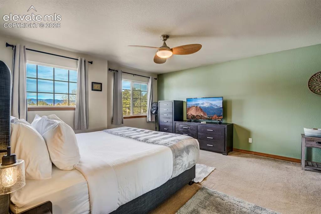 Image 16 of 45: Room featuring two grid-pattern windows with mountain scenery, a ceiling fa