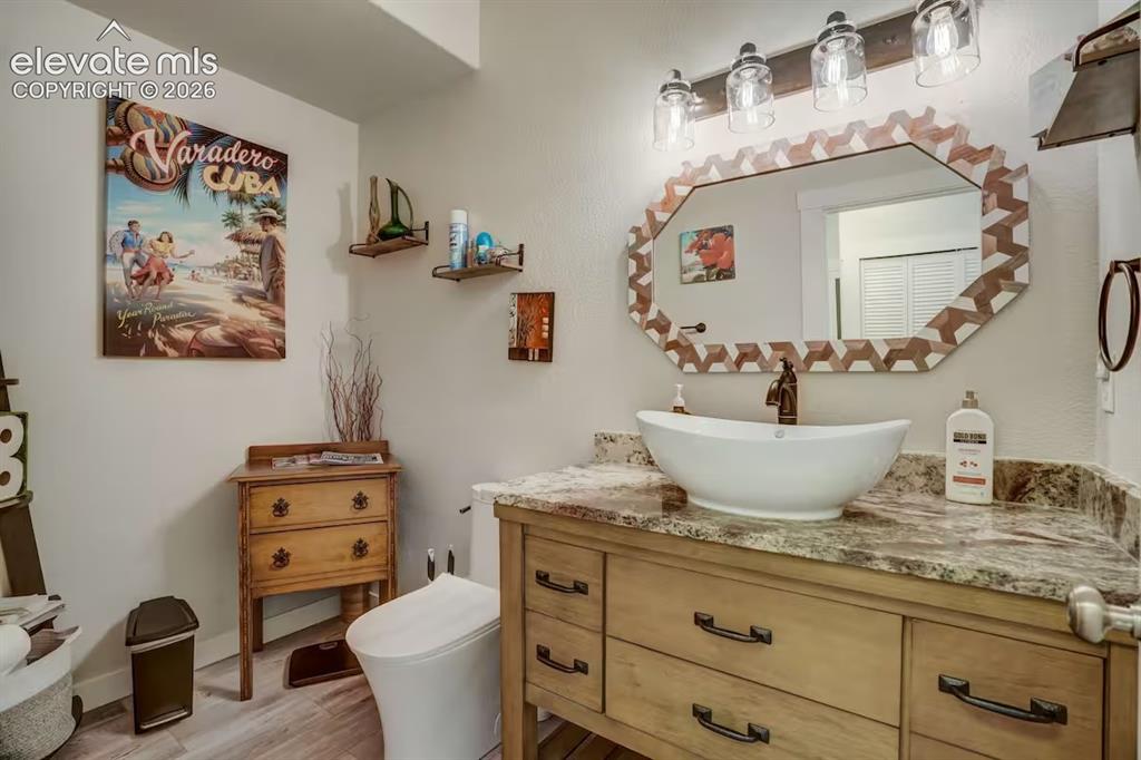 Image 17 of 45: Vanity with a vessel sink, stone countertop, and wood-finish cabinetry
