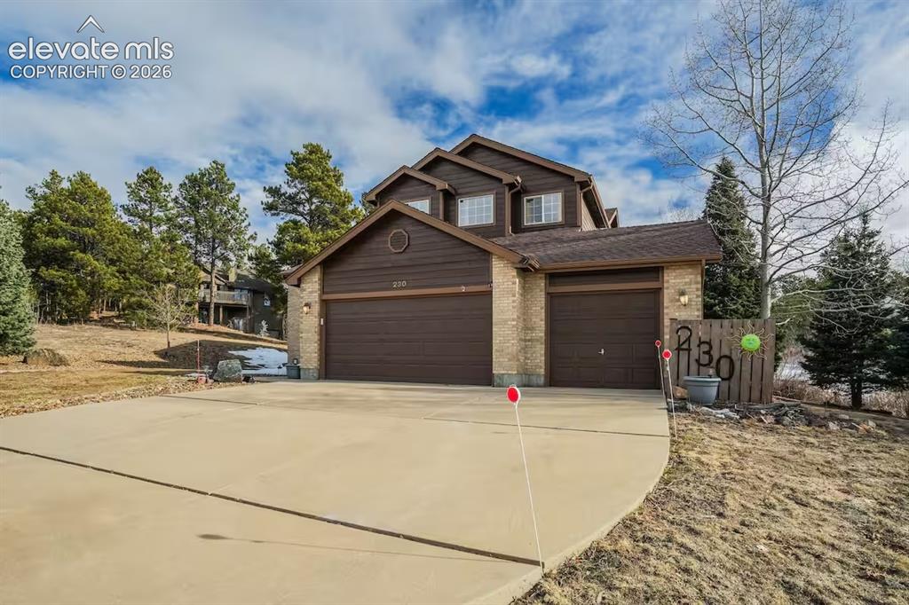 Image 2 of 45: Multi-level property featuring a brown wood-paneled exterior, brick accents