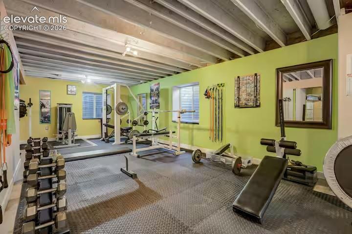 Image 21 of 45: Dedicated fitness space featuring a rubber mat flooring system and exposed