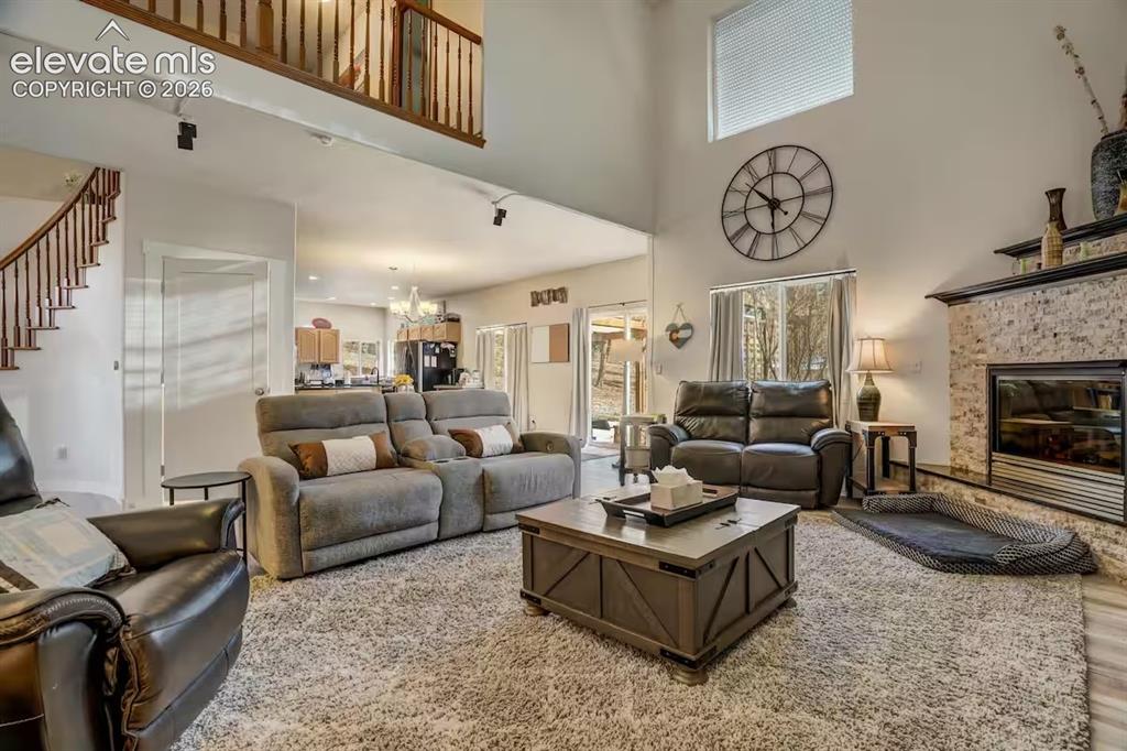 Image 22 of 45: Vaulted living space featuring a stone-clad fireplace, high ceilings, large