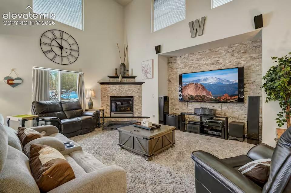 Image 26 of 45: Spacious living area featuring a stone-clad fireplace with a dark wood mant