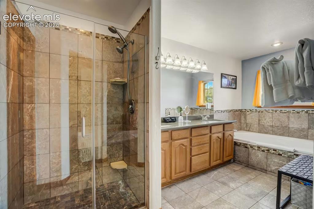 Image 28 of 45: Spacious bathroom featuring a glass-enclosed shower with stone-look tile, a