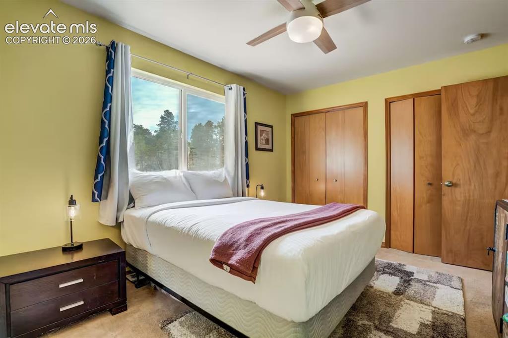Image 30 of 45: Bedroom featuring a large window, light wood-finish doors, a ceiling fan wi