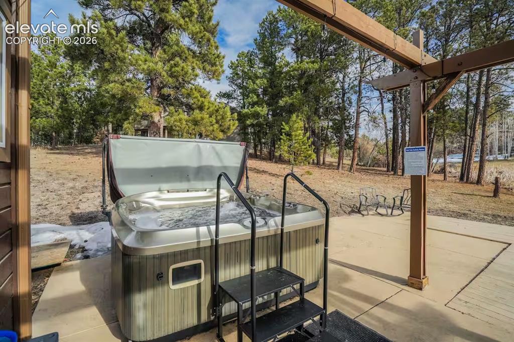 Image 42 of 45: Outdoor spa with integrated steps, situated on a concrete patio