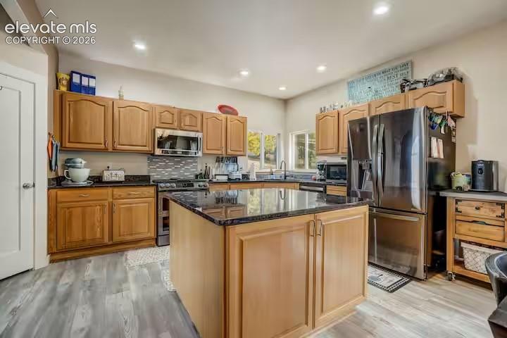 Image 8 of 45: Kitchen featuring a central island with a dark countertop, stainless steel