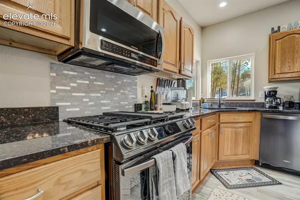 Image 9 of 45: Kitchen featuring a stainless steel range with overhead microwave, dark gra