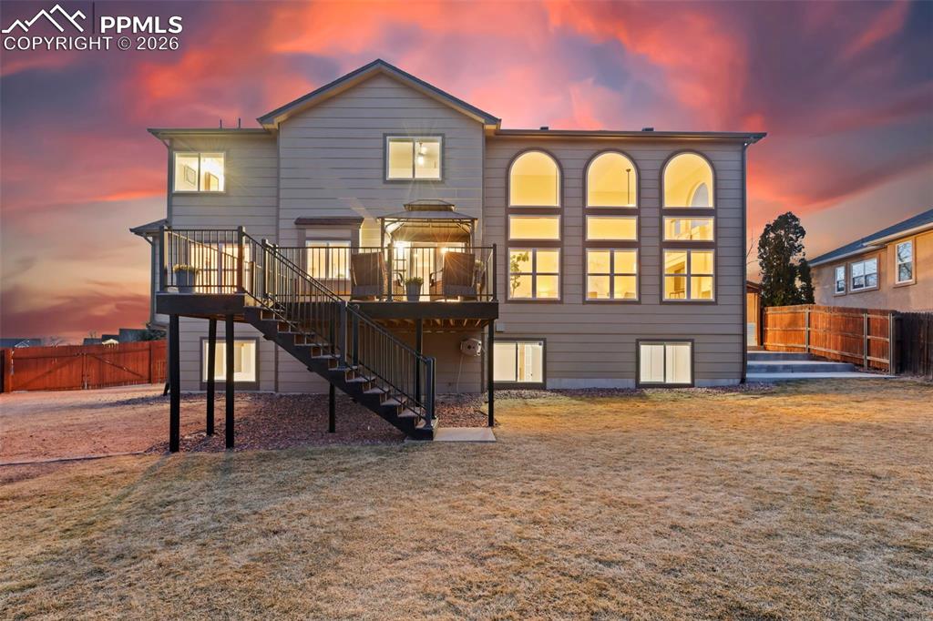 Image 47 of 50: Back of house at dusk featuring a fenced backyard, a patio, and a deck