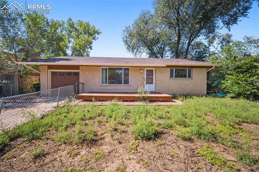 Caption: Single story home with a deck, an attached garage, and brick siding